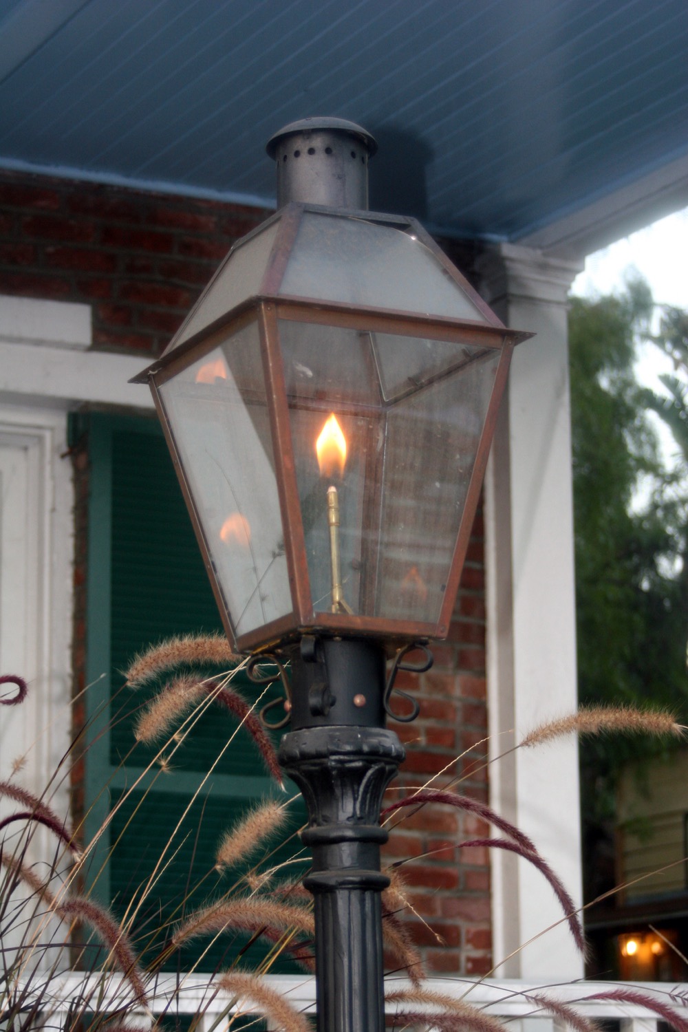 A propane-powered gas lamp in front of a brick house. 