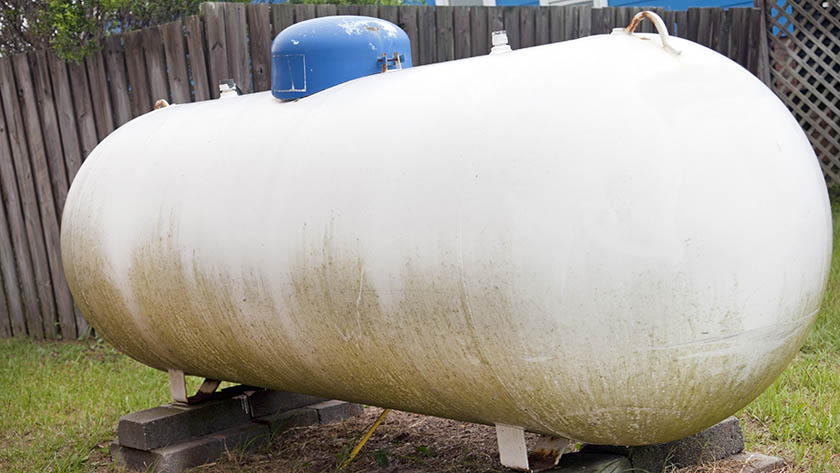 White propane tank in a residential backyard. 