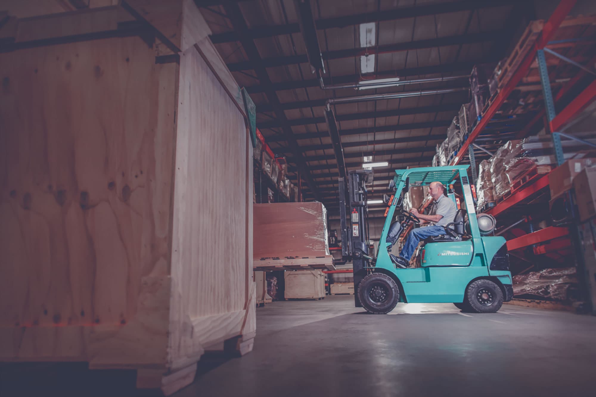 Propane-powered Forklift moving a skid onto a warehouse shelf.