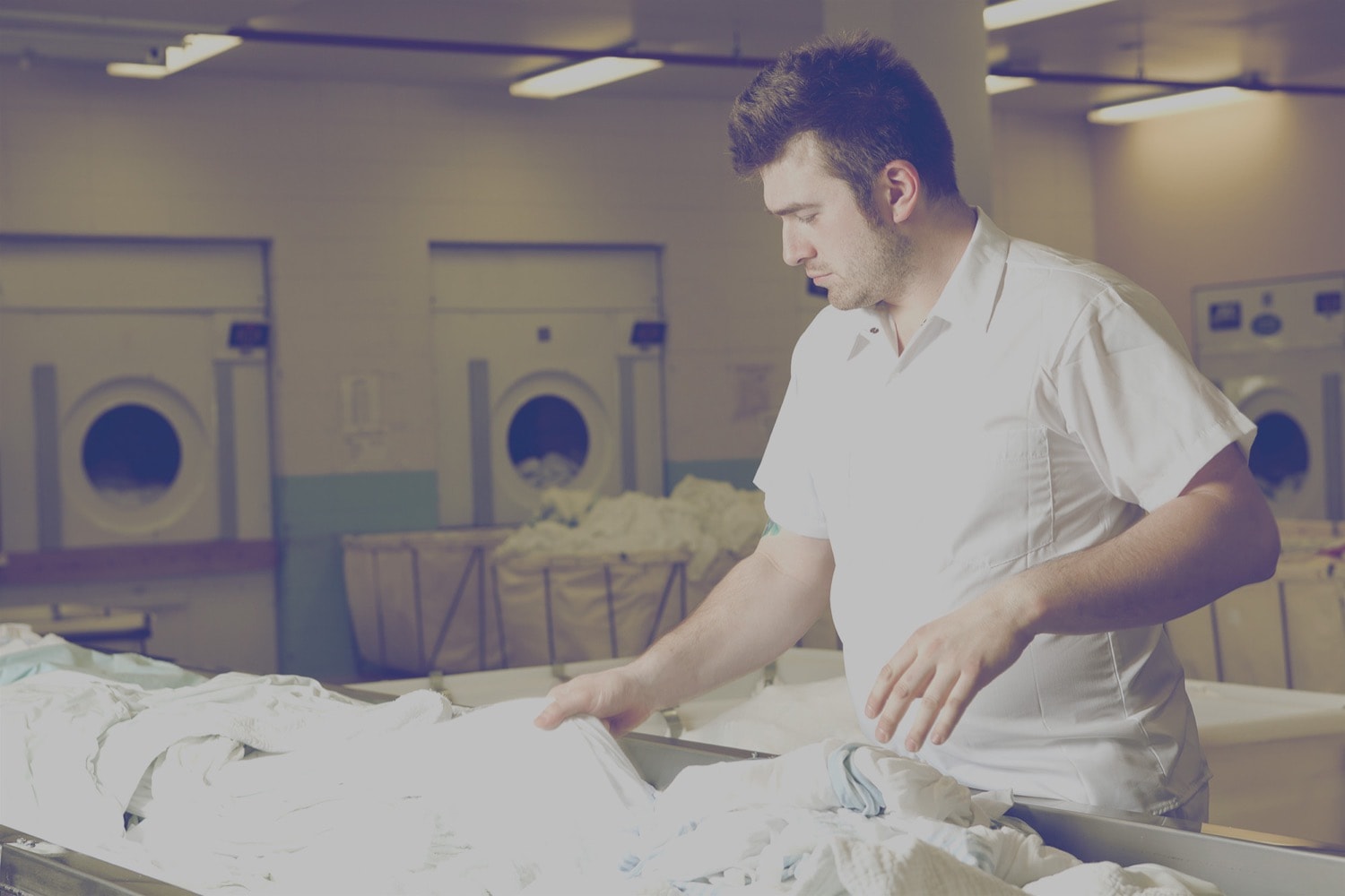 Male standing in front of laundry hampers in the laundry room of a hotel. 