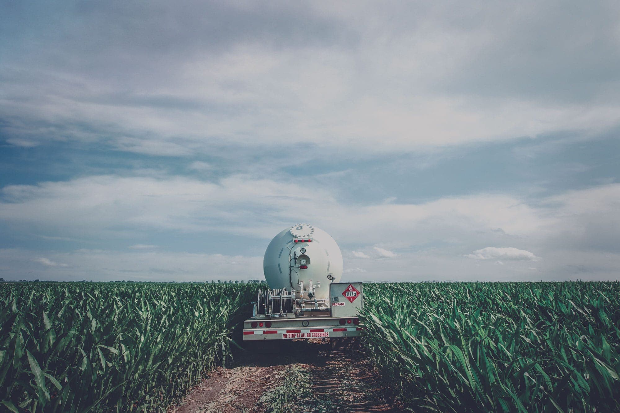 A propane truck driving through a corn field.