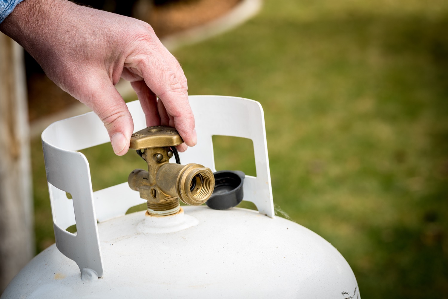 Closeup of a man adjusting the top of a propane barbeque cylinder. 