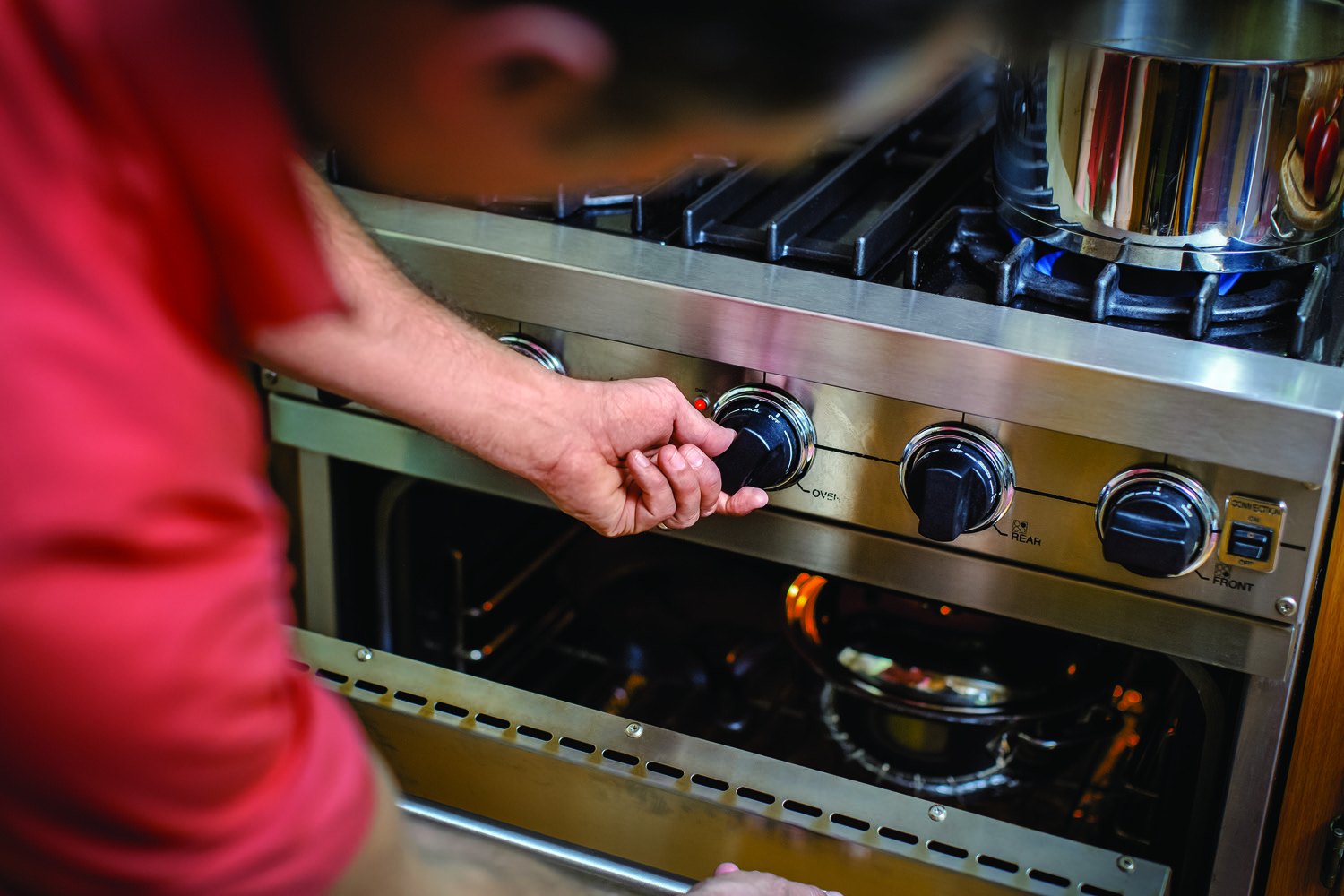 Man adjusting the dial on a propane range in a kitchen. 