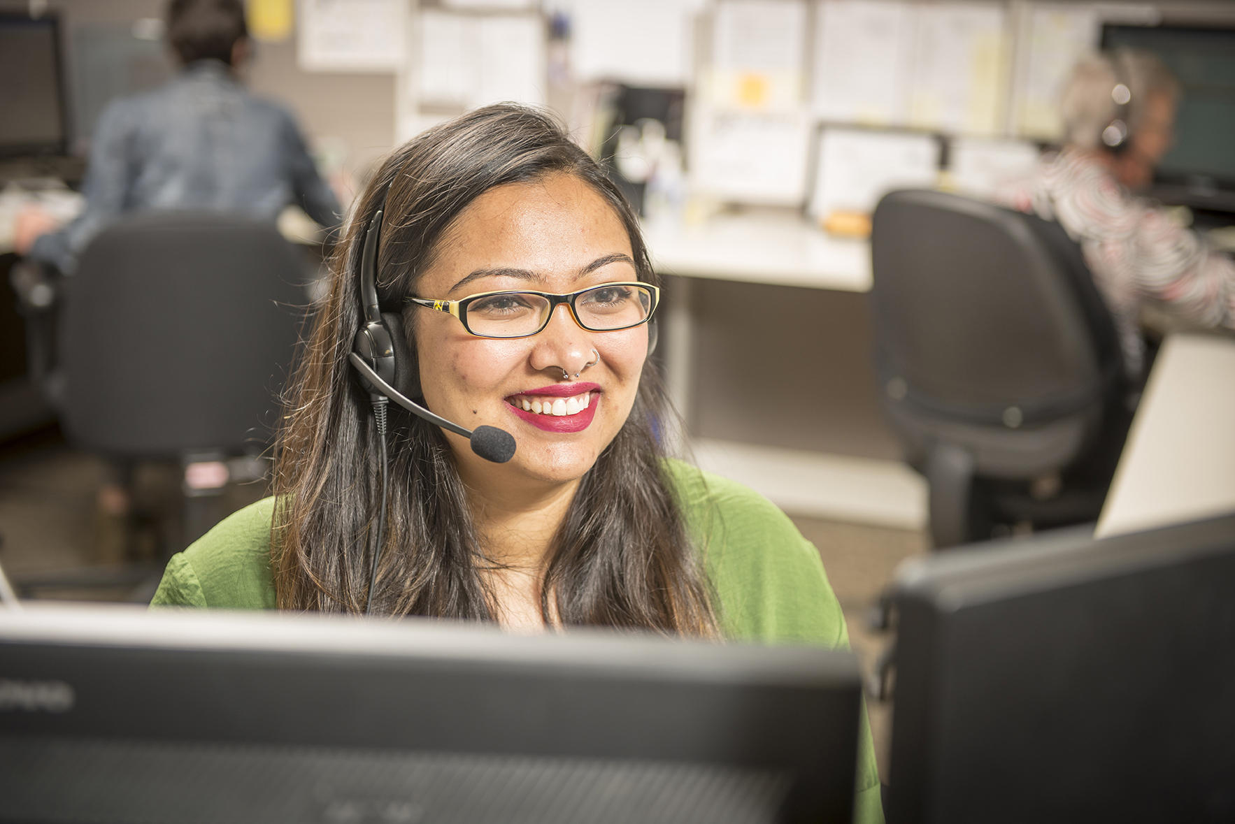 Smiling customer support representative with hands-free headset working in the office